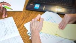 Two students making making notes in multiple notebooks